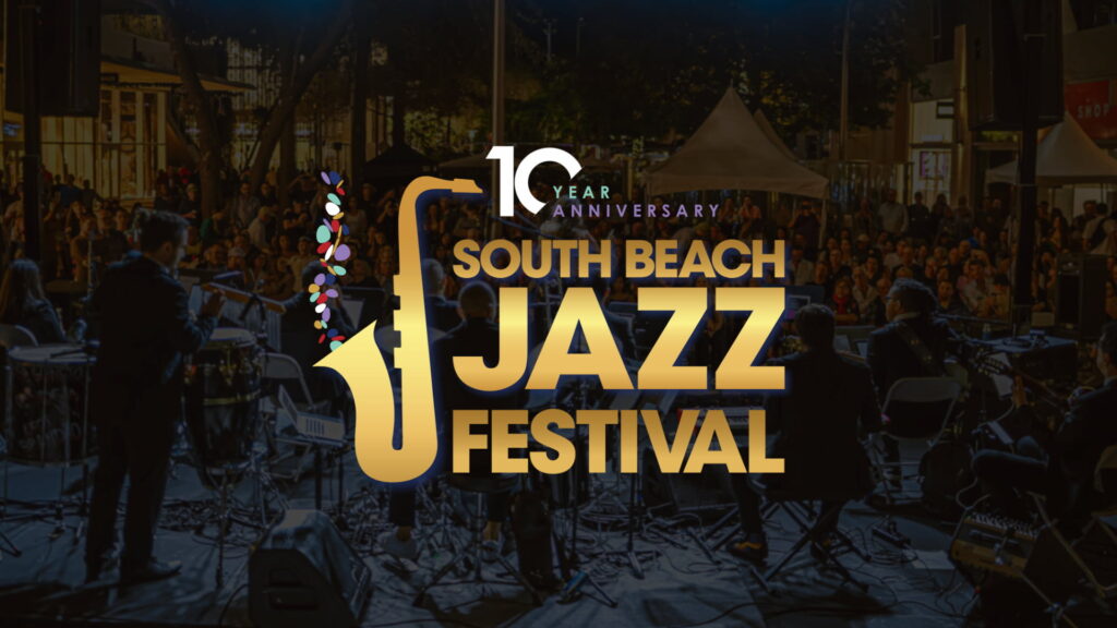 Musicians perform on stage at night before a large outdoor audience during the South Beach Jazz Festival. Overlaid on the photo is the festival’s 10th anniversary logo featuring a golden saxophone and the words ‘South Beach Jazz Festival.’