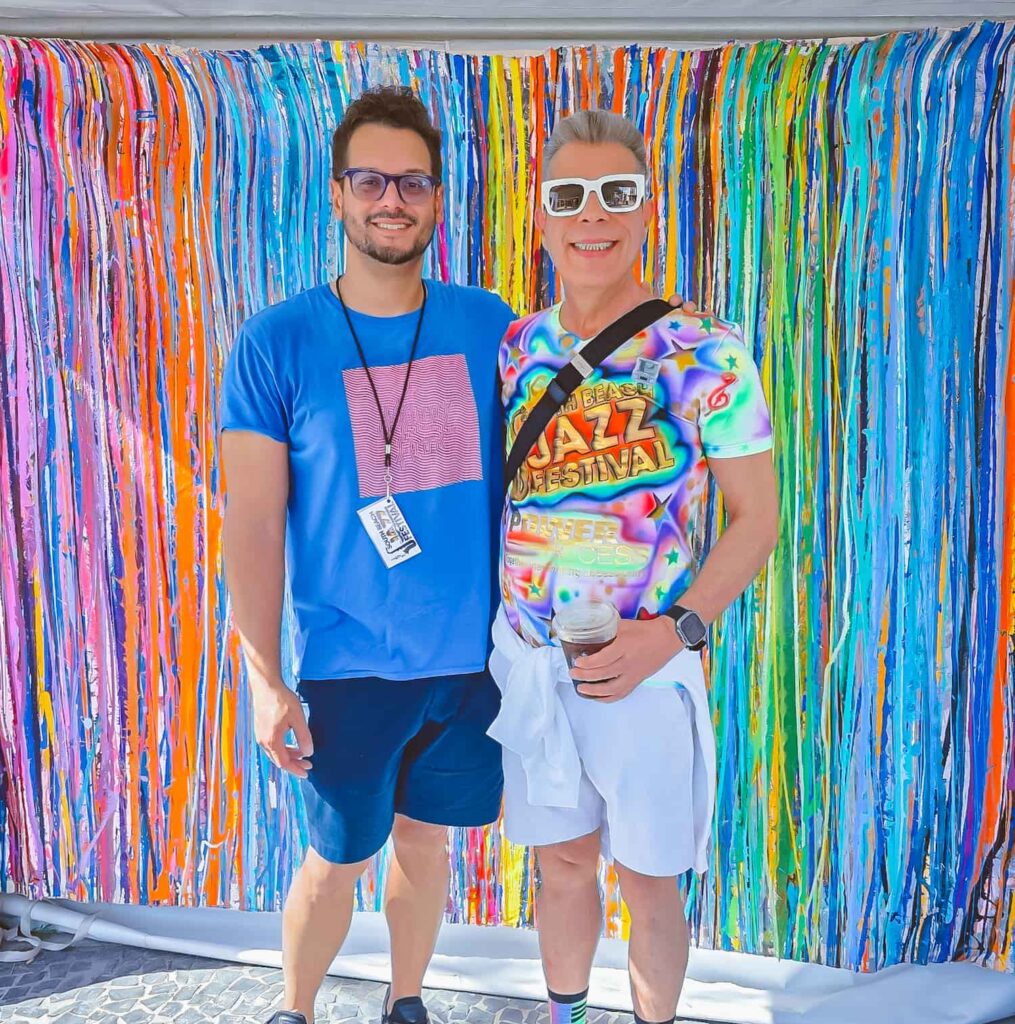 David New with another South Beach Jazz Festival attendee posing in front of a colorful art backdrop on Lincoln Road in Miami Beach.