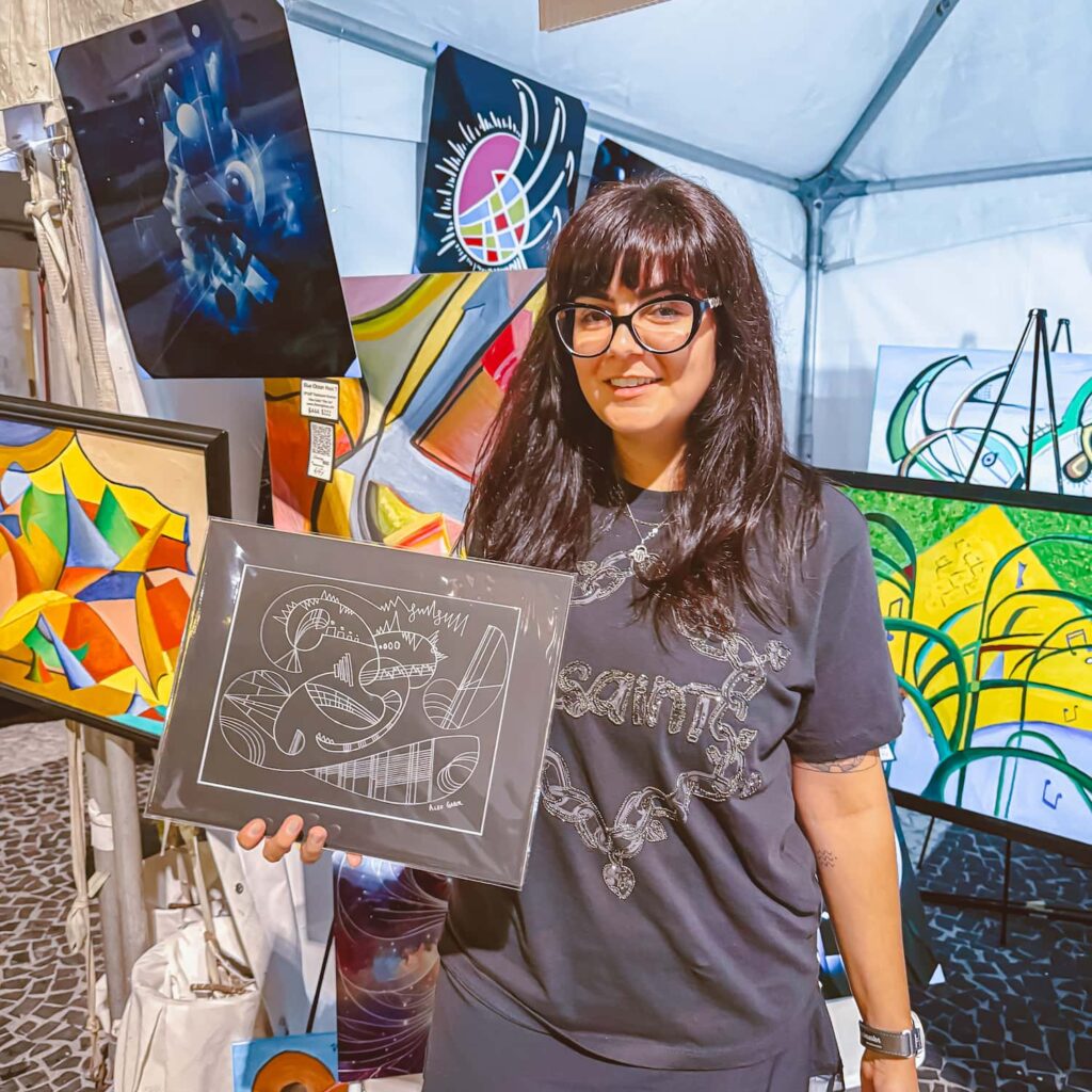 Visual artist holding an original jazz inspired artwork at her art booth during the South Beach Jazz Festival on Lincoln Road in Miami Beach